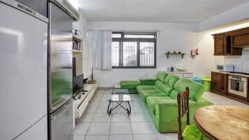 Un soggiorno con un divano verde, una TV e un tavolo da pranzo.