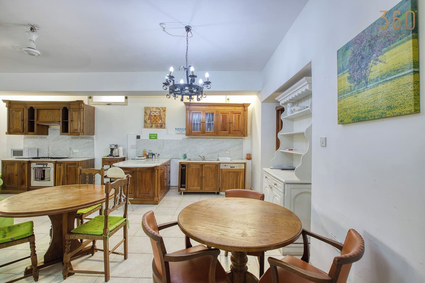 Una cucina con mobili in legno, un tavolo da pranzo con sedie e un lampadario.
