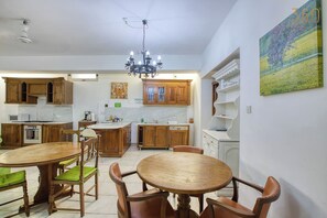 Una cucina con mobili in legno, un tavolo da pranzo con sedie e un lampadario.