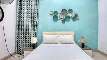 Una camera da letto con un letto, due comodini, una ventola a parete, una tenda e un elemento decorativo a parete.