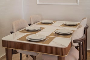 A dining table with four chairs, each with a placemat and a plate. - Heaven Beach (Sidi Rahal)
