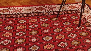 A room with a sofa covered in a floral pattern, a small table with a decorative item, and a patterned rug. - Small Apartments City Center Retreat (Sarajevo)