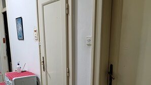 A laundry area with a washing machine, a door, and a wall-mounted light switch. - Small Apartments City Center Retreat (Sarajevo)