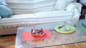 A glass-top coffee table with a woven basket and a green plate, a striped sofa, and a wooden parquet floor. - Small Apartments City Center Retreat (Sarajevo)