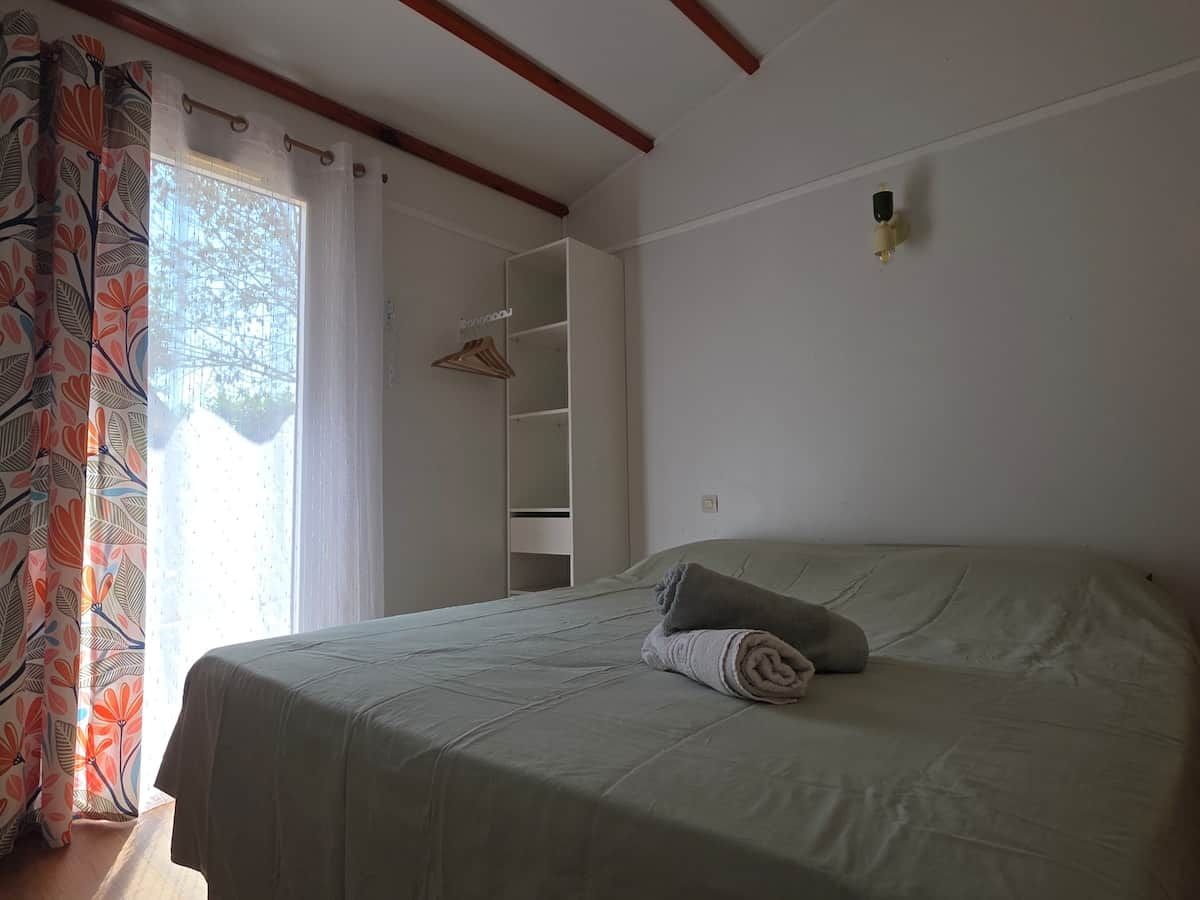 A bedroom with a bed, a wardrobe, and a window with curtains.