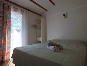 A bedroom with a bed, a wardrobe, and a window with curtains.