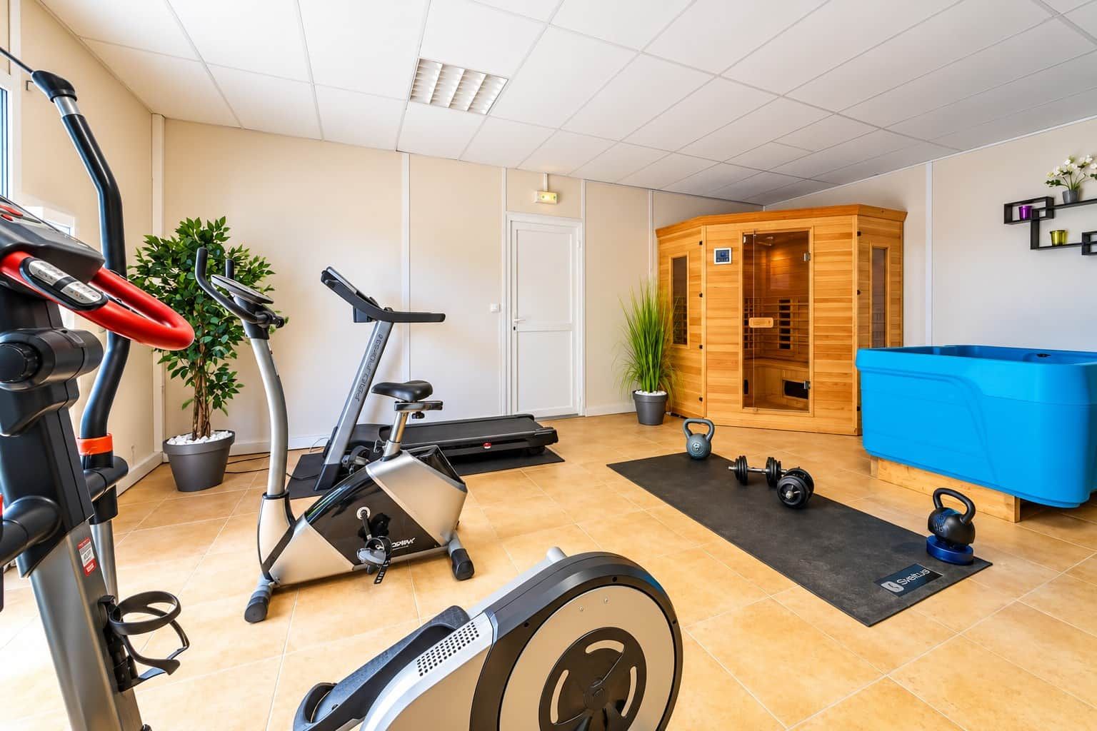 Un gimnasio en casa con equipo de ejercicio, una sauna y una mesa de billar azul.