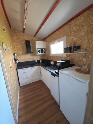 A compact kitchen with a microwave, coffee maker, and a small refrigerator.