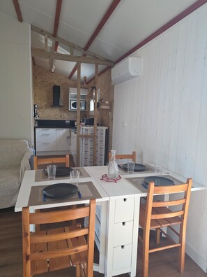 A dining area with a white table, wooden chairs, and a kitchen in the background.