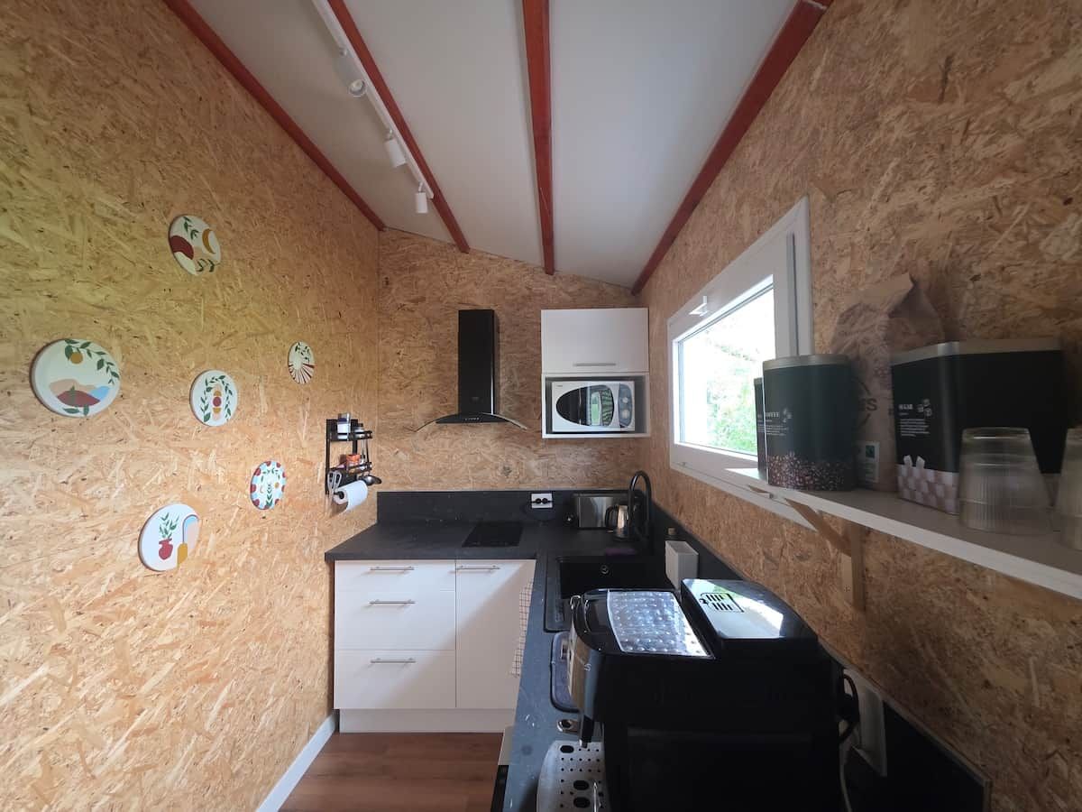 A compact kitchen with a microwave, sink, and a small window.