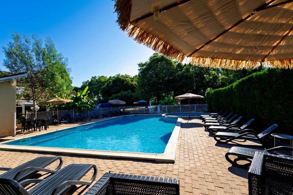 A swimming pool with lounge chairs and umbrellas.