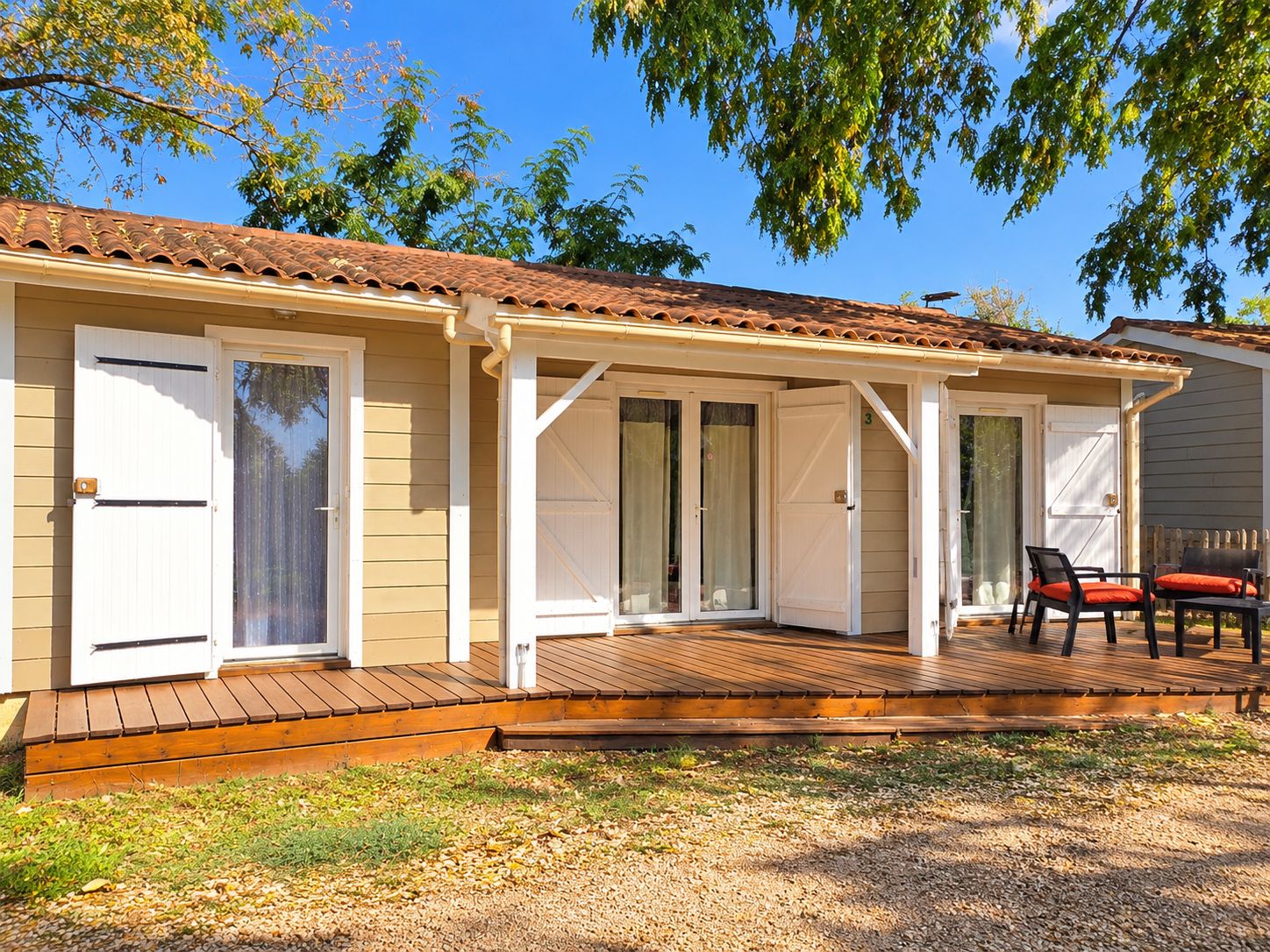 A single-story building with a covered patio area, a door, and a small outdoor seating area.