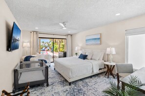 A hotel room with a bed, a desk, a chair, a TV, and a view of the pool area. - Waterfront 5BR Estate w/ Heated Pool | Walk to Cocoa Beach (Cocoa Beach)