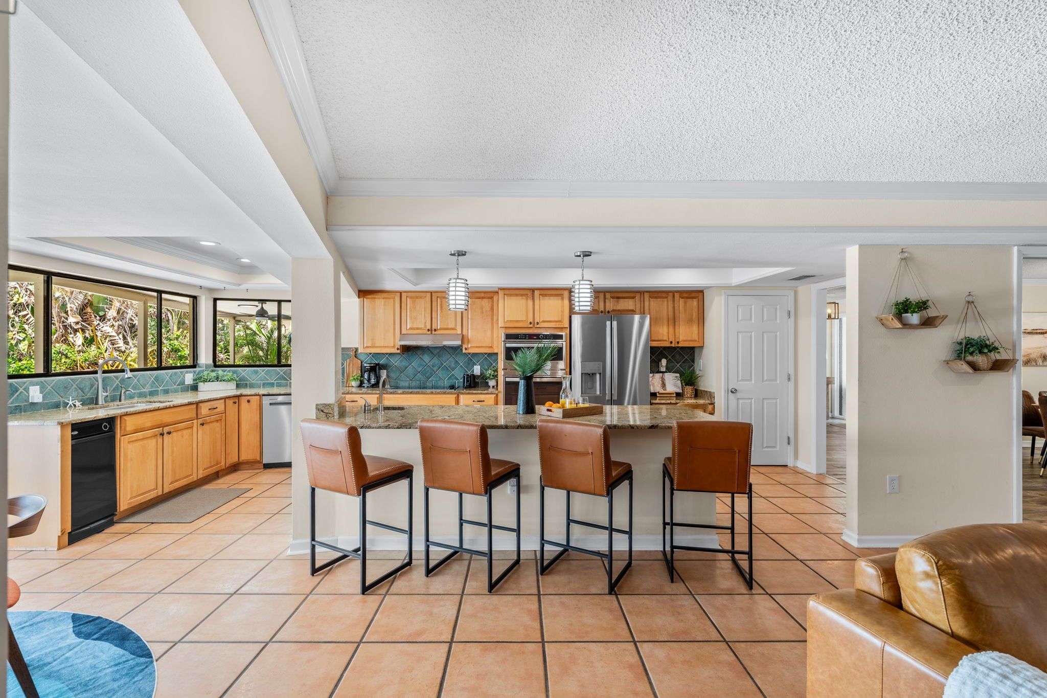 A modern kitchen with wooden cabinets, a central island with bar stools, and a large refrigerator.