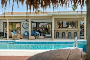 A poolside area with lounge chairs and a covered seating area. - Waterfront 5BR Estate w/ Heated Pool | Walk to Cocoa Beach (Cocoa Beach)