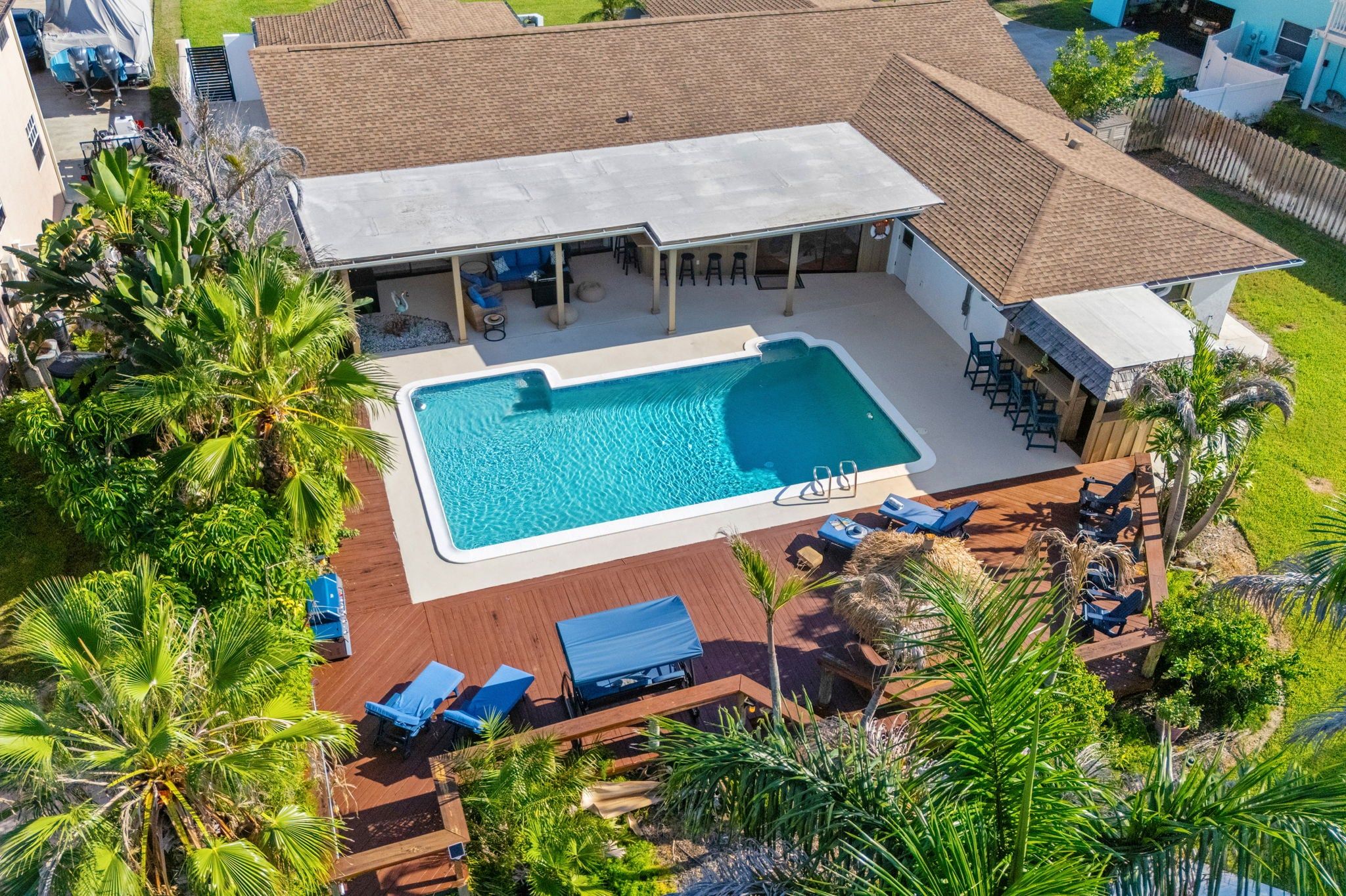Un área de piscina en la azotea con una piscina rectangular, sillas de descanso y un espacio de estar cubierto.