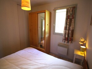 A bedroom with a bed, a wardrobe, a window with curtains, a radiator, and a bedside lamp. - Quiet apartment with parking, pets OK - 4 guests, mountain view (Bagnères-de-Luchon)