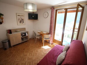 A room with a bed, a desk, a chair, a television, and a window with a view. - Quiet apartment with parking, pets OK - 4 guests, mountain view (Bagnères-de-Luchon)