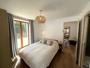 Ein Schlafzimmer mit einem großen Bett, einer Hängeleuchte und Blick auf einen Balkon.