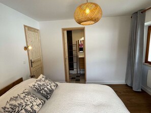 Een slaapkamer met een bed, een deur, een spiegel en een hanglamp.