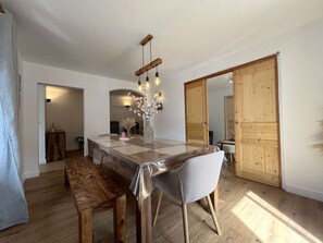 Ein Essbereich mit einem Holztisch, Stühlen und einer Vase mit Blumen.