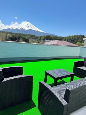 A rooftop terrace with wicker furniture and a view of a snow-capped mountain.