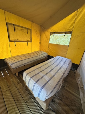 Une tente avec deux lits, une fenêtre et un plancher en bois.