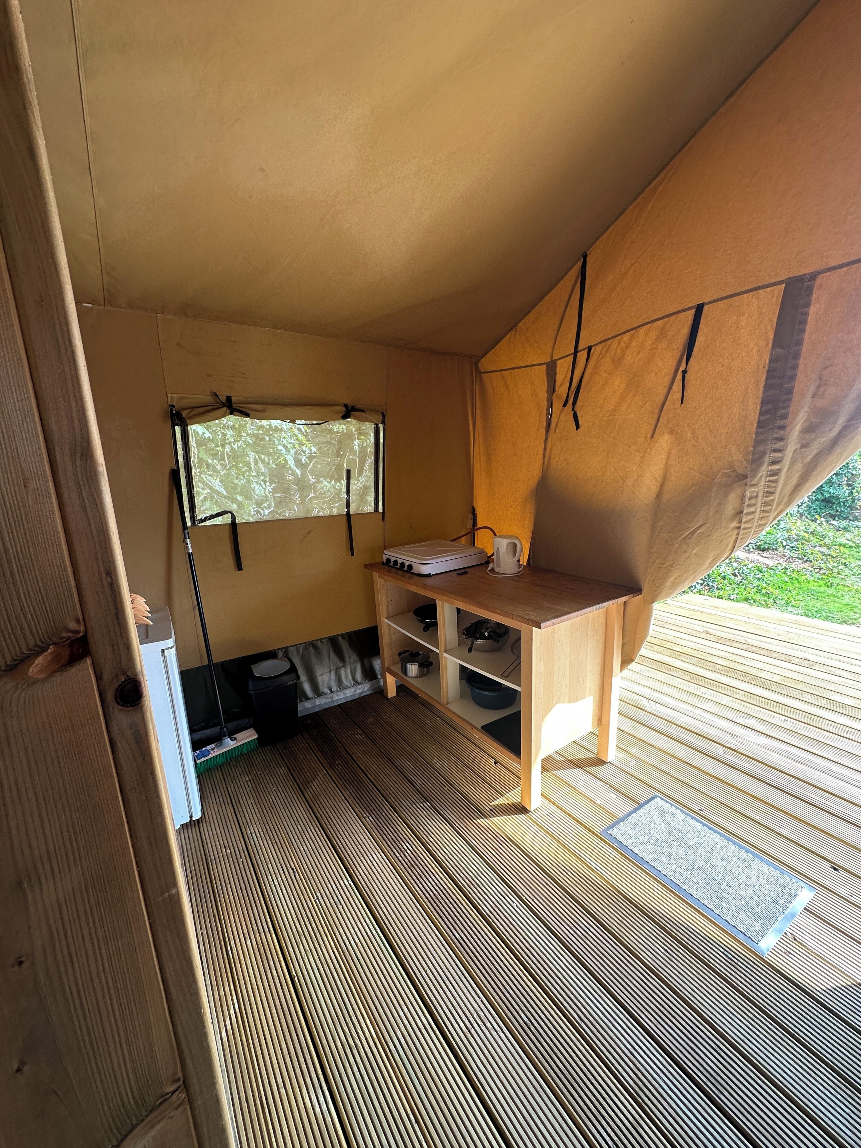 A compact room with a wooden desk, a window, and a small kitchenette area.