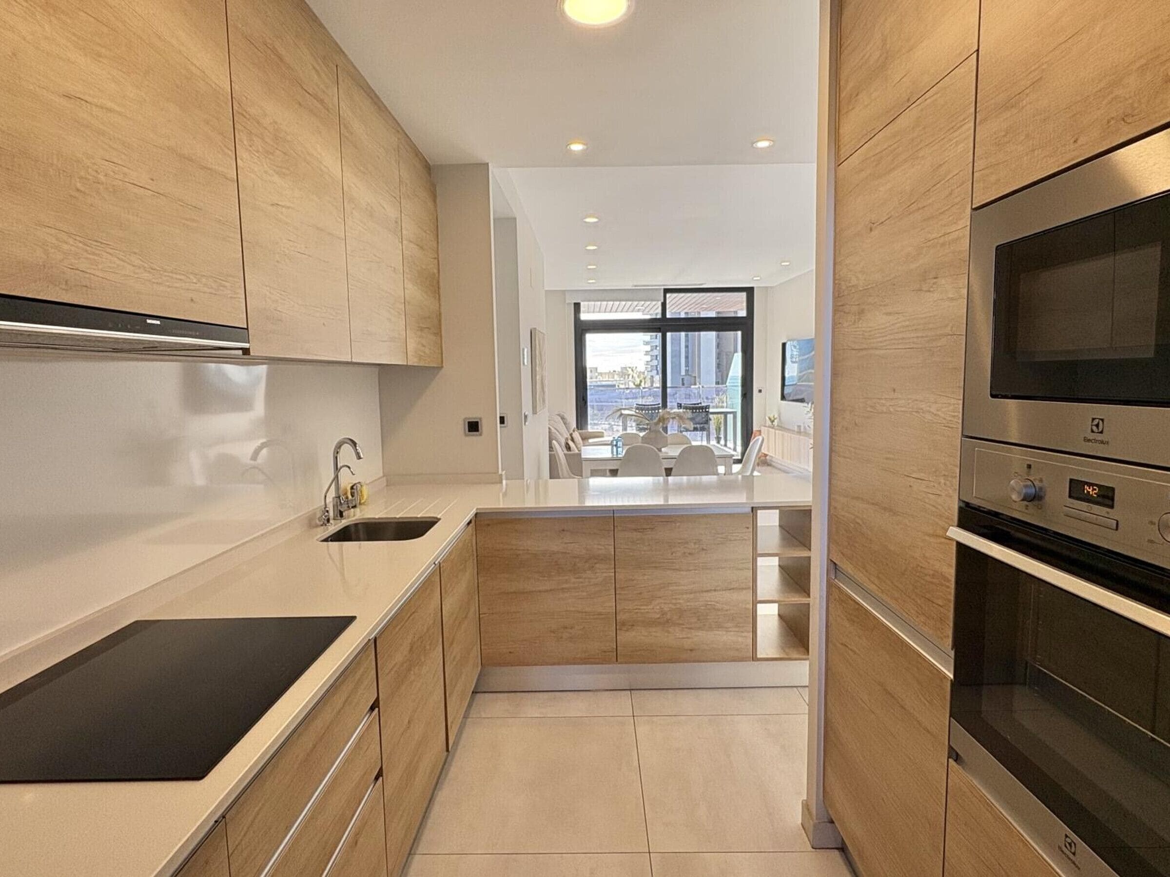 A modern kitchen with wooden cabinets, a stainless steel sink, and a built-in oven.