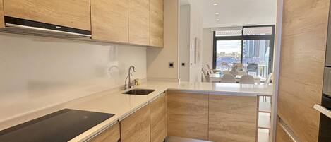A modern kitchen with wooden cabinets, a black countertop, and a view to a dining area.