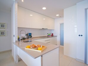 Eine moderne Küche mit weißen Schränken, einem Einbauofen und einem Frühstücksbrett mit Croissants und Orangensaft.