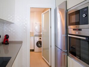 Eine Küche mit Waschmaschine, Kühlschrank und Mikrowelle.