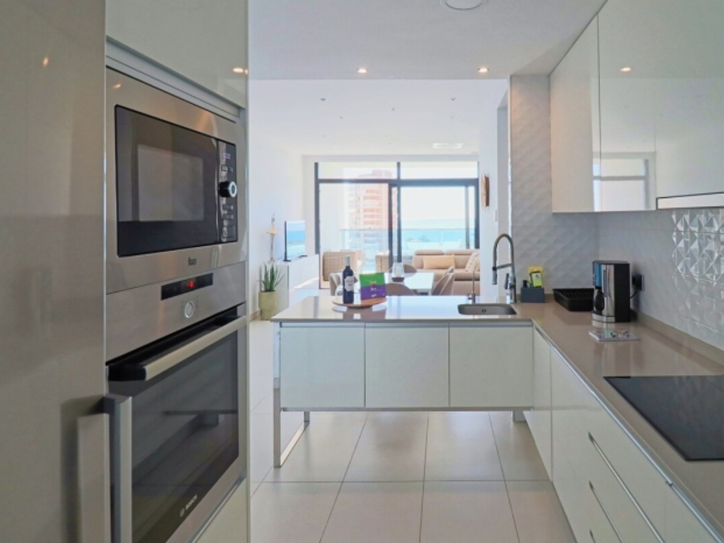 A modern kitchen with a built-in microwave, oven, and a central island with a sink.