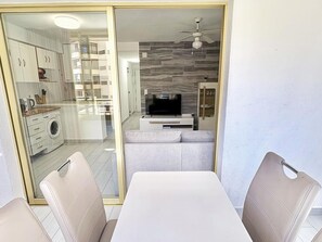 Uma sala de estar moderna com televisão de tela plana, ventilador de teto e sofá.
