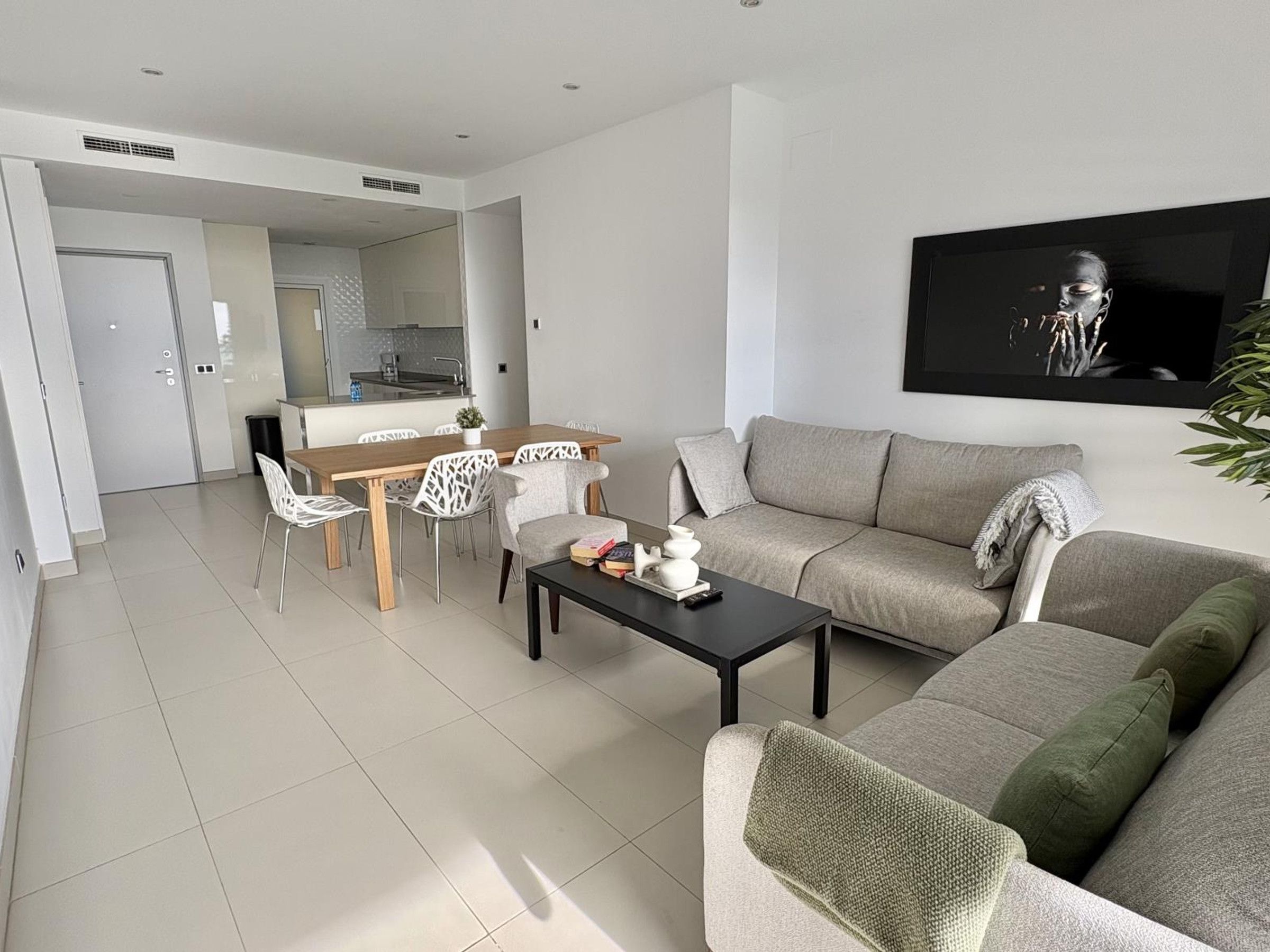 A modern living room with a sofa, coffee table, and dining area.