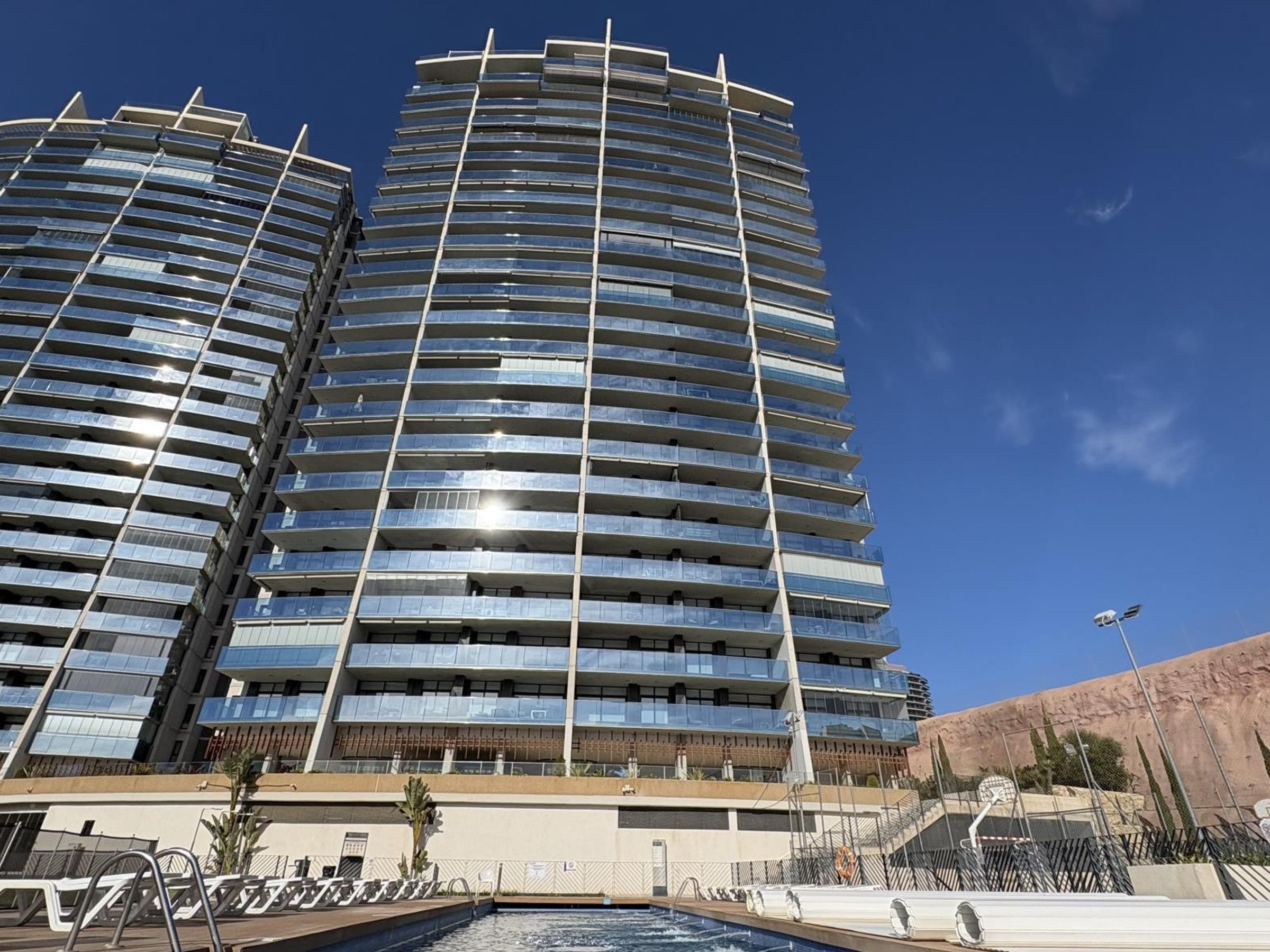 A high-rise hotel with multiple balconies and a swimming pool area.