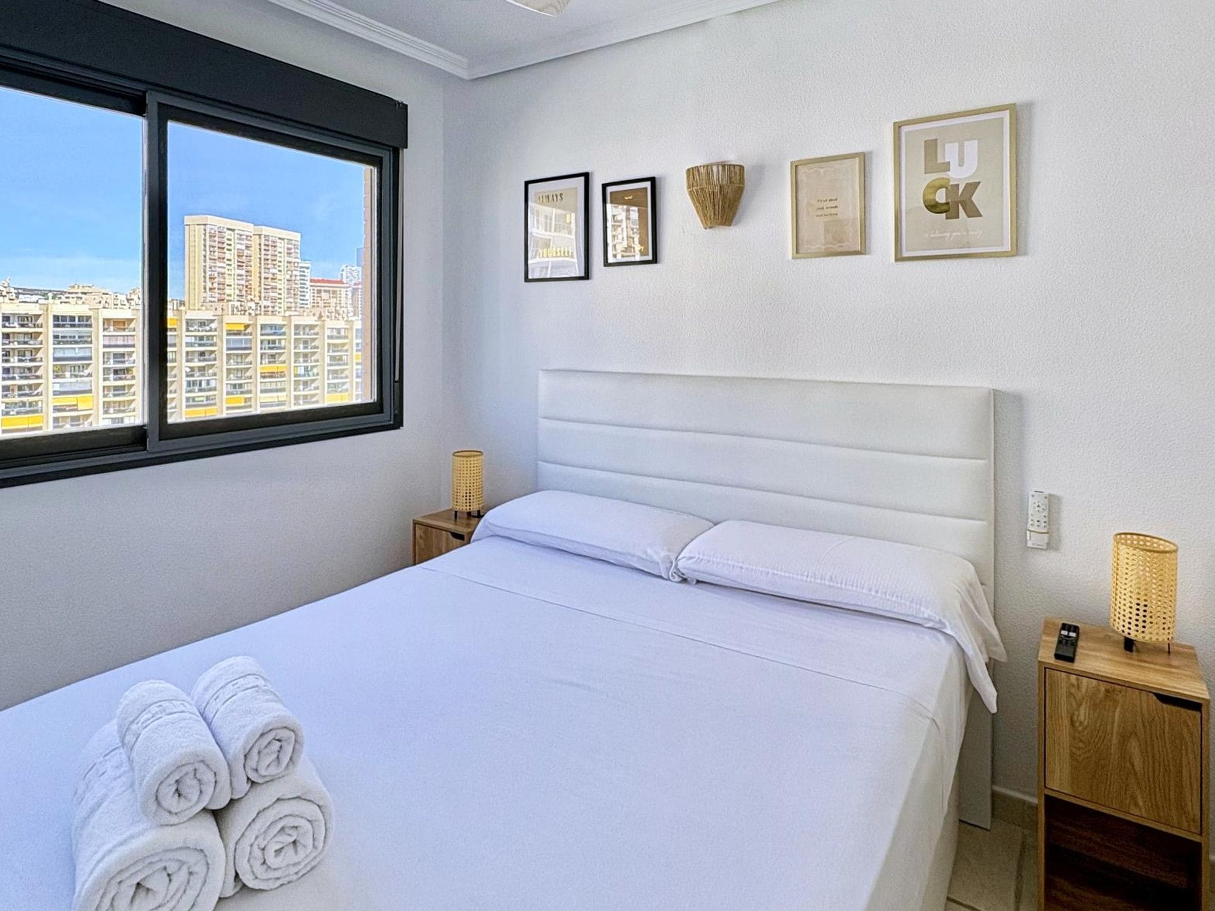 A hotel room with a bed, a window, and wall-mounted decor.