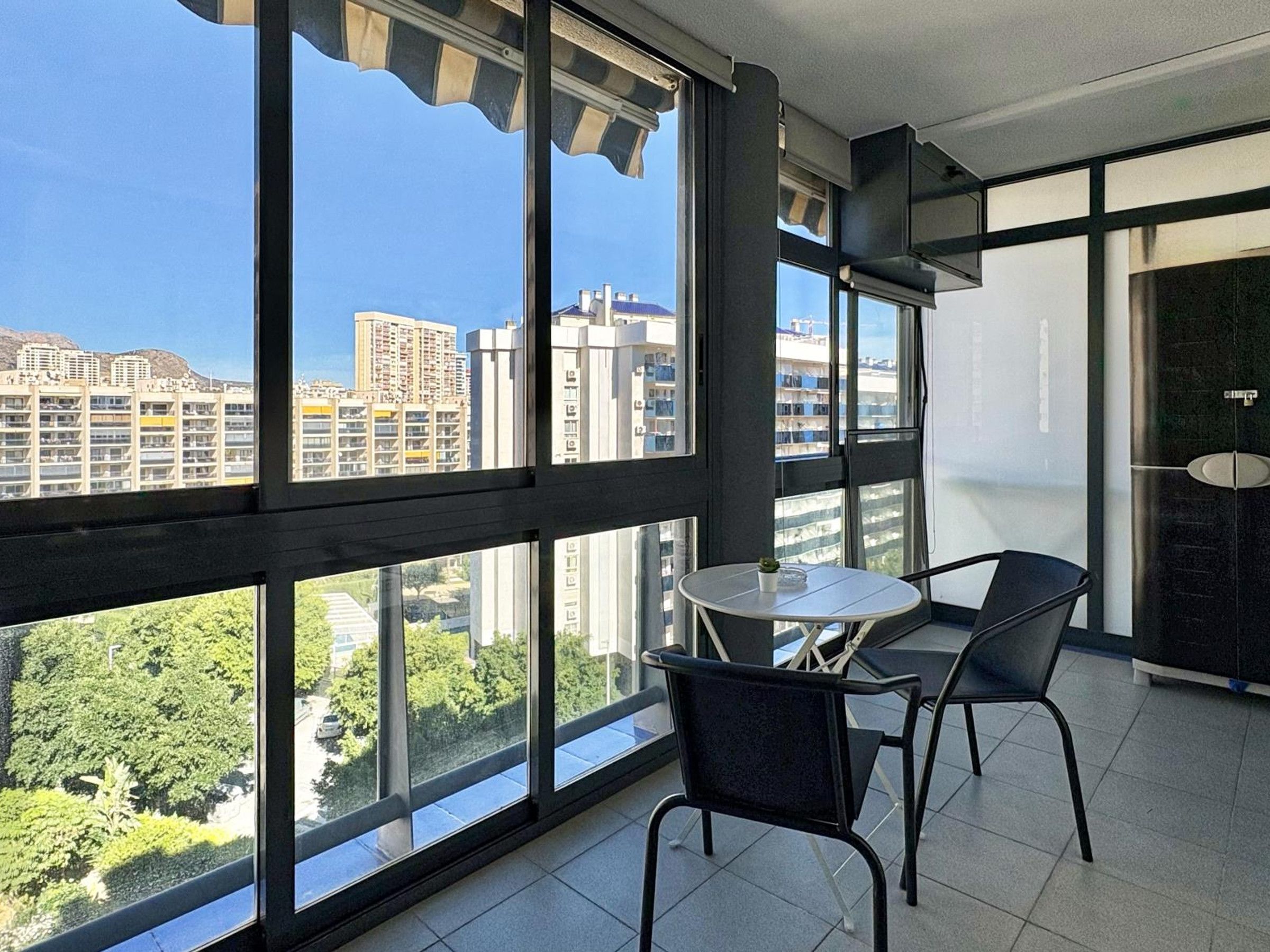 Un balcon donnant sur un paysage urbain, une table ronde et deux chaises.