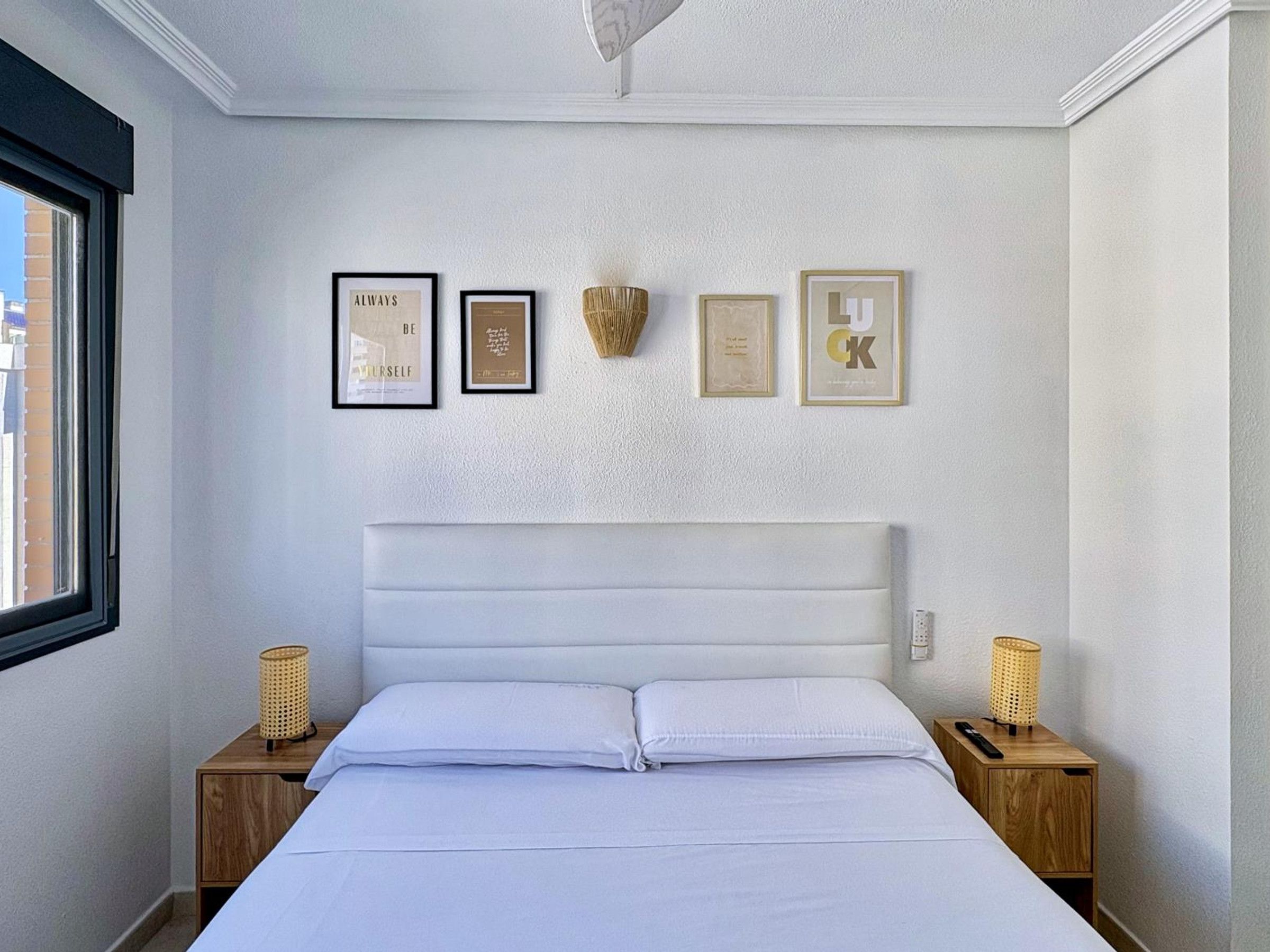 Une chambre à coucher avec un lit, deux tables de chevet et quatre objets encadrés accrochés au mur.