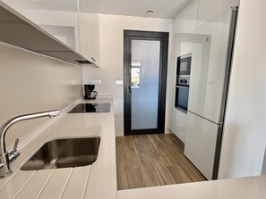 Eine moderne Küche mit Spüle aus Edelstahl, einer Kaffeemaschine und einem Kühlschrank.