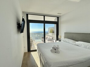 Habitación de hotel con cama, televisión y un ventanal con vistas a la ciudad.