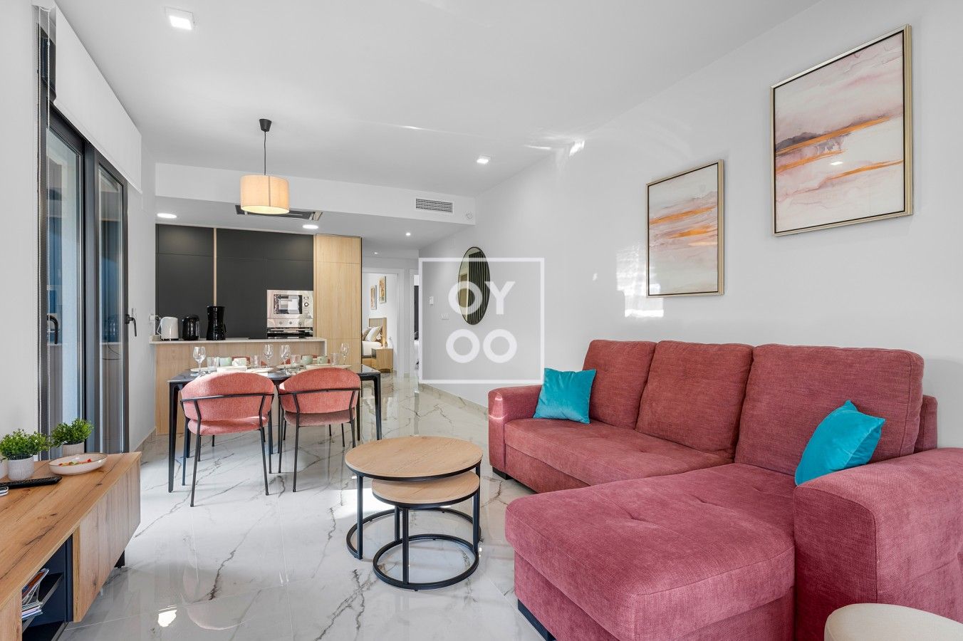A modern living room with a red sofa, a dining area with a table and chairs, and a kitchen in the background.