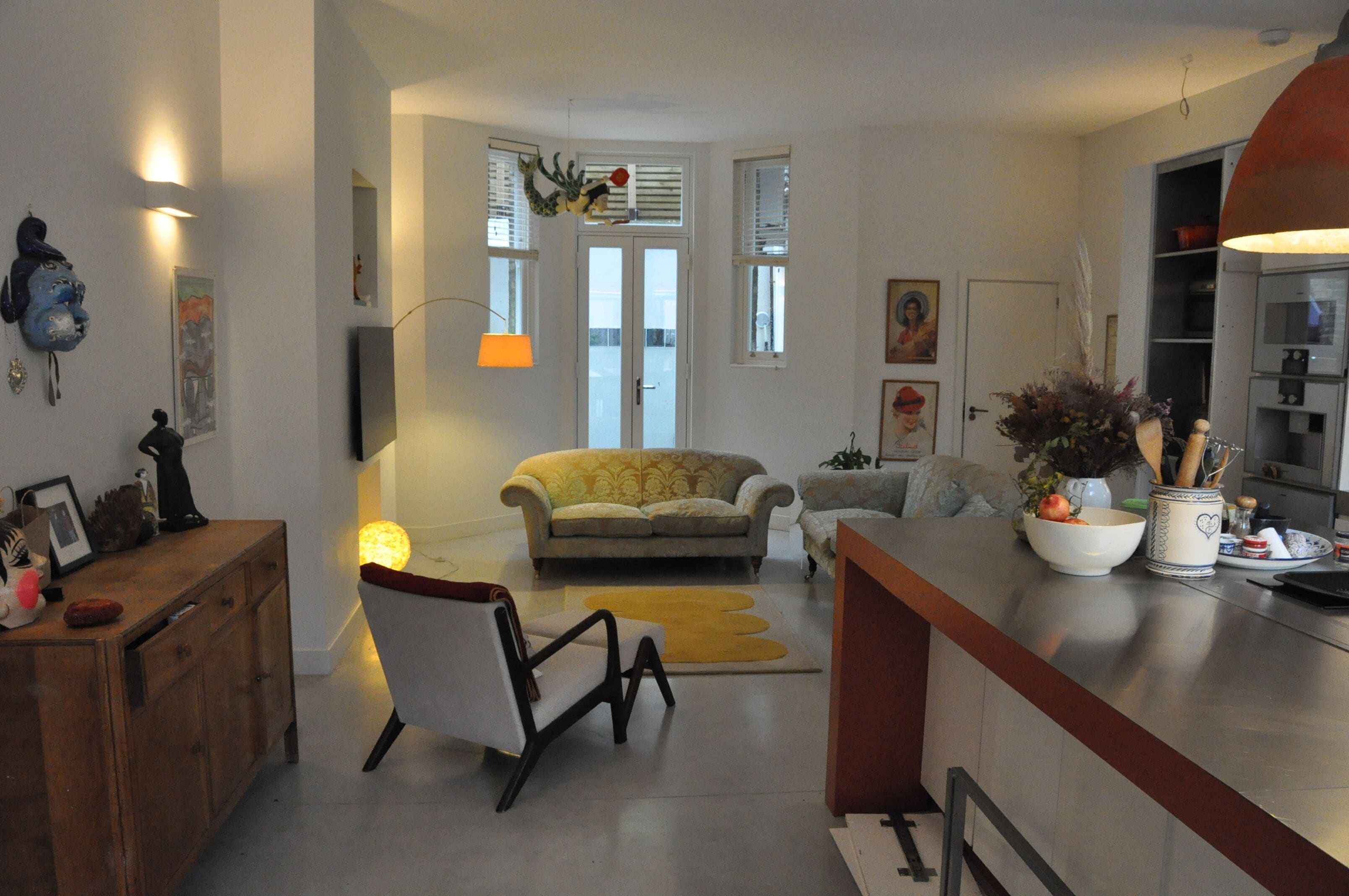 A spacious living area with a sofa, a dining table, and a kitchen area with cabinets and a stove.