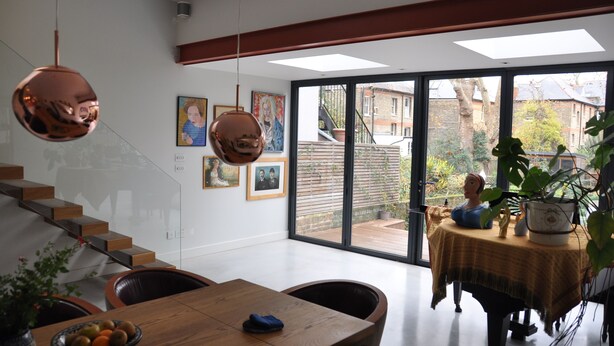 A modern interior with a dining area, a staircase, and a view through large windows. - Design-Led Islington Home with Huge Private Garden (London)