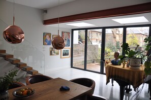 A modern interior with a dining area, a staircase, and a view through large windows. - Design-Led Islington Home with Huge Private Garden (London)