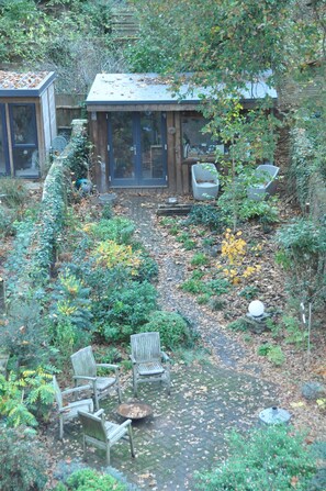 A garden with a patio area, including two chairs and a small table. - Design-Led Islington Home with Huge Private Garden (London)
