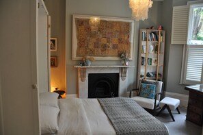 A bedroom with a fireplace, a bed, a bookshelf, and a window. - Design-Led Islington Home with Huge Private Garden (London)