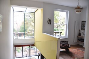 A room with a yellow staircase, large windows, a zebra wall decoration, and a chandelier. - Design-Led Islington Home with Huge Private Garden (London)