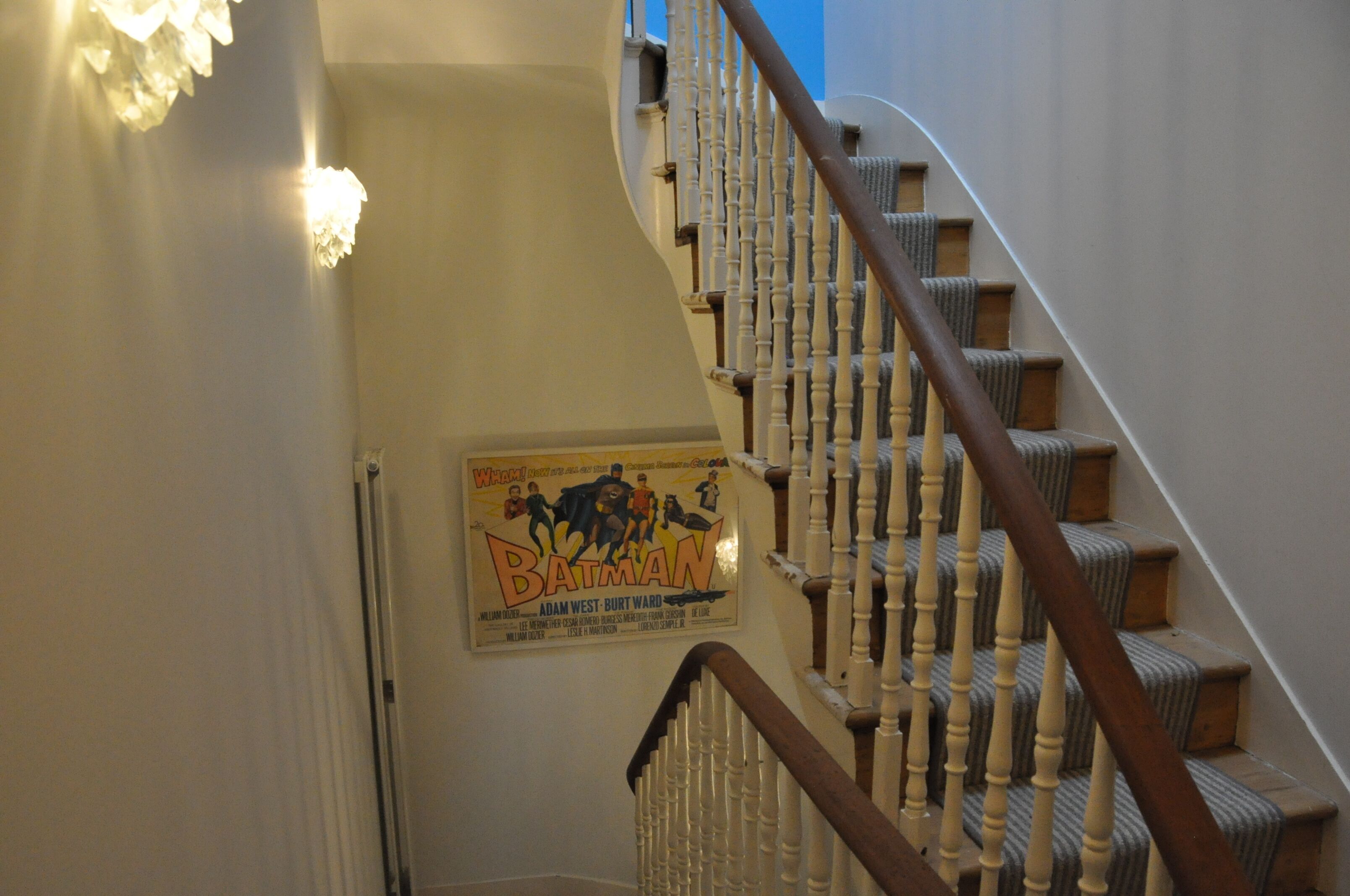 Un escalier avec une rampe en bois et une affiche de film accrochée au mur.