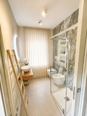 A modern bathroom with a glass-enclosed shower, a vanity with a sink, and a toilet. - Vrbo Property (arezzo)